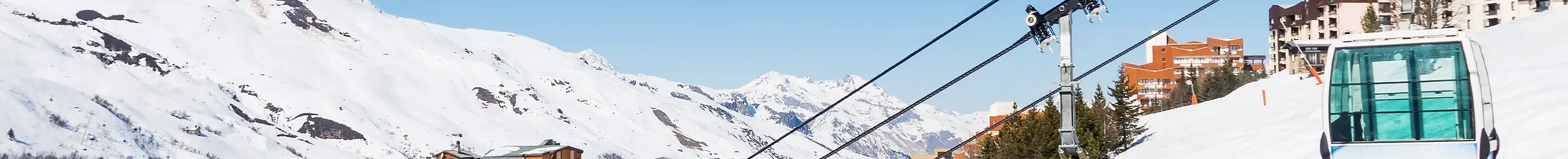 une remontée mécanique avec en fond un paysage de montagnes enneigées