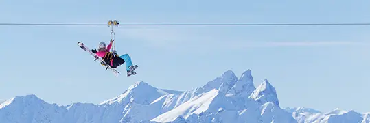 Une femme en tyrolienne à travers les montagnes enneigées