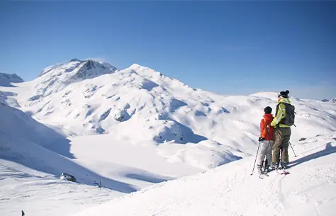 Un couple qui contemple un paysage de montagnes enneigées