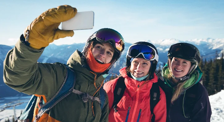 Trois amies se prennent en selfie avec un fond de montagnes enneigées