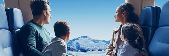 Une famille dans un train qui contemple la vue d'un paysage montagneux et enneigé