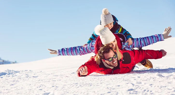 Famille qui glisse sur le ventre sur la neige