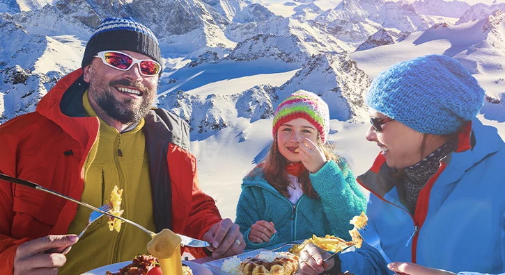 famille qui profite une raclette à la montagne