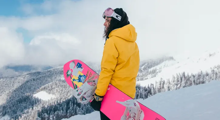Une snowboardeuse qui admire la vue du haut d'une montagne