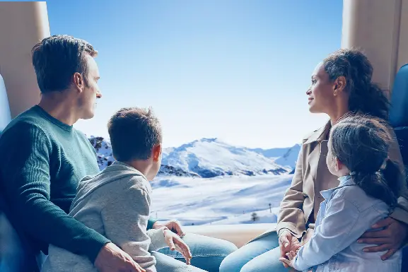 Une famille dans un train qui admire la vue d'un paysage montagneux et enneigé
