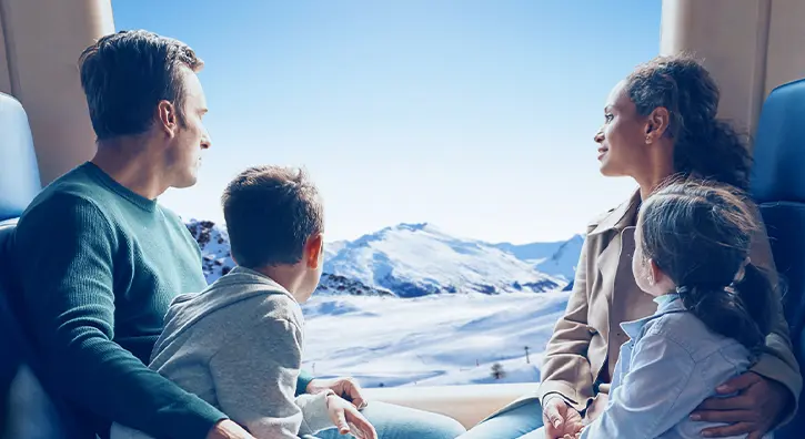 Une famille qui admire un paysage montagneux et enneigé dans un train