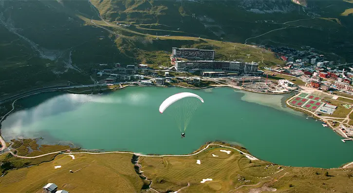 Parapente au dessus d'un lac à Tignes en été