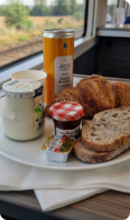 Petit-déjeuner servi à bord : croissant, pain, yaourt, confiture et jus d'orange